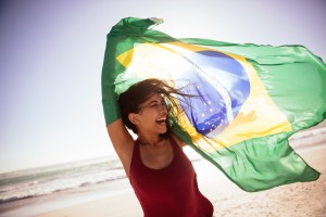 Frau hält eine brasilianische Flagge am Strand